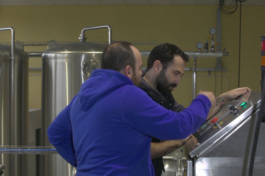 two men doing maintenance work of control screen of beer brewing system at 'Sknipa' plant